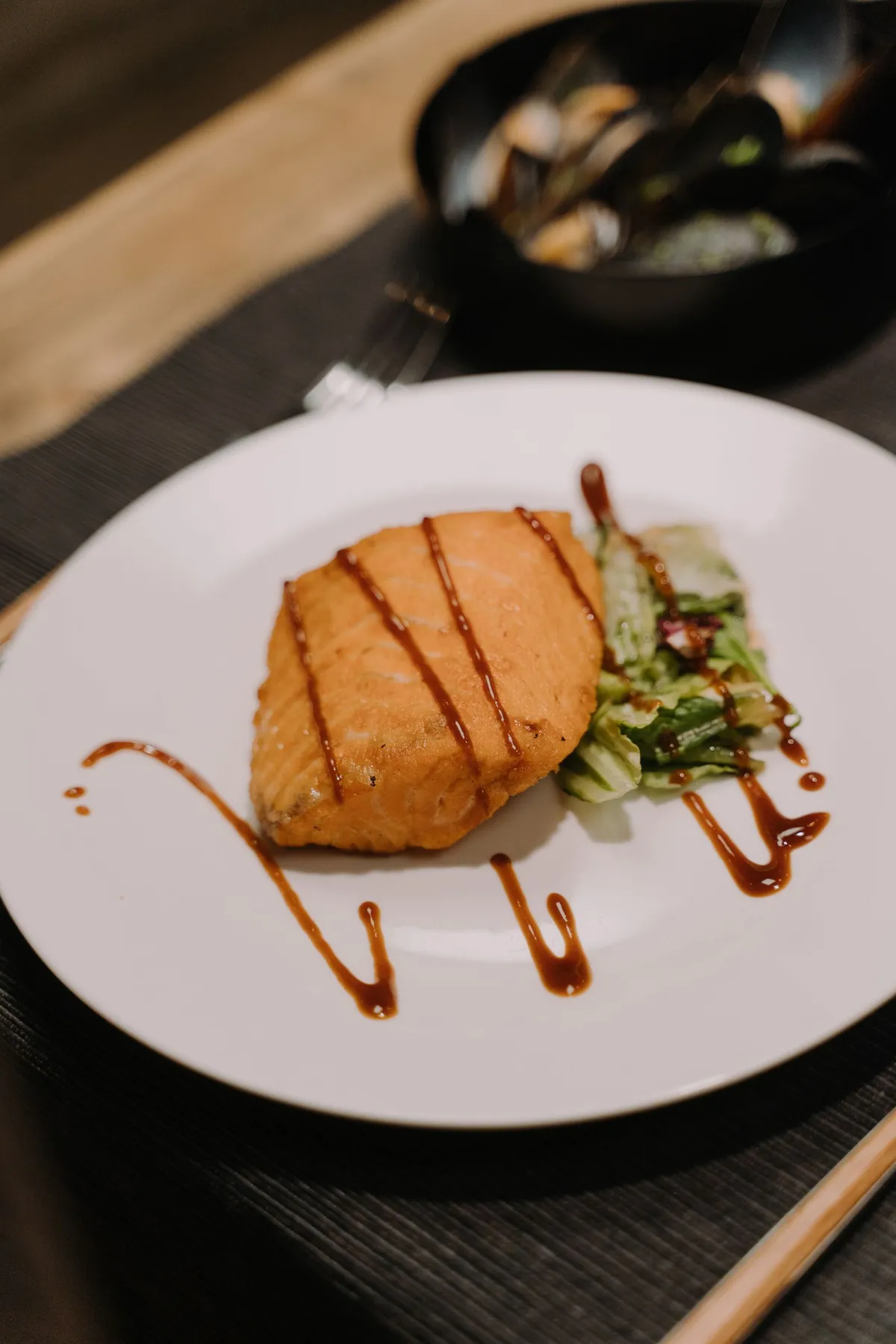 Filete de pescado cocinado servido en un plato blanco con ensalada
