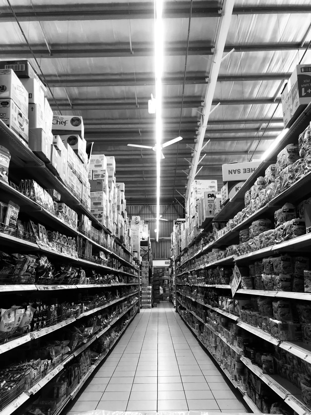 Pasillo de supermercado con estanterías llenas de productos vistas en perspectiva.