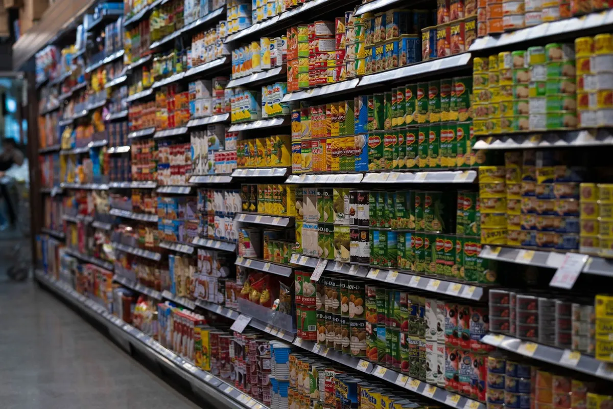 Pasillo de supermercado con estanterías llenas de conservas y alimentos