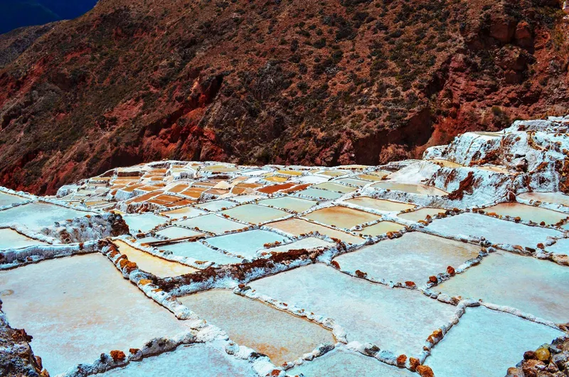 Terrazas escalonadas de sal en una salina junto a la ladera de la montaña